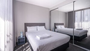 Un hotel moderno con una cama grande, una mesita de noche, un espejo y vistas a la ciudad desde la ventana.