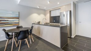 Una cocina moderna con una isla central, electrodomésticos de acero inoxidable y un comedor con sillas negras.