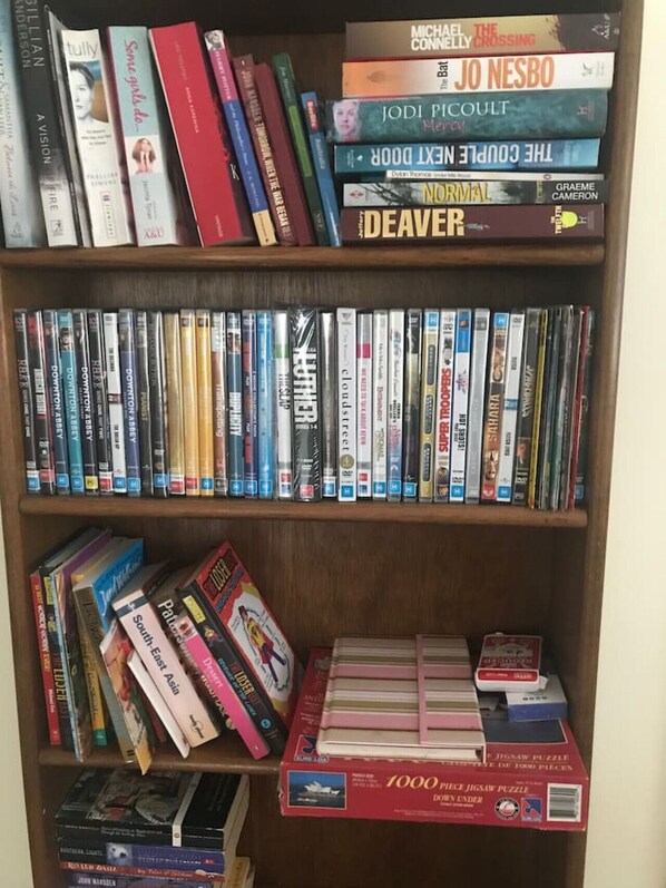 A bookshelf with a variety of books and DVDs, including titles like 'The Crossing' and 'The Girl with the Dragon Tattoo'.