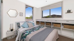 Een moderne slaapkamer met een groot bed, een raam met uitzicht en ingebouwde opbergruimte.