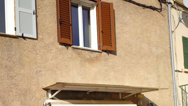 A building with a rustic facade, large wooden doors, and a small awning over the entrance. - Village house in central Corsica very close to Corte and its University  (Omessa)