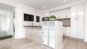 Una cucina moderna con mobili bianchi, un frigorifero con sportello in vetro e un forno integrato.