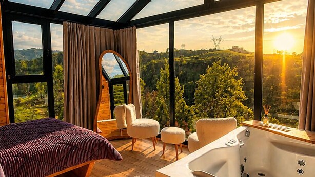Une chambre avec une grande fenêtre, un lit, un coin salon et une baignoire.