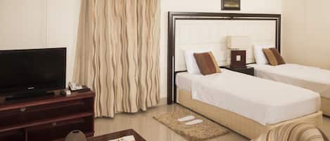 Quarto de hotel com cama, televisão, escrivaninha e cadeira.