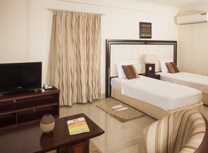 Ein Hotelzimmer mit Bett, Fernseher, Schreibtisch und Stuhl.