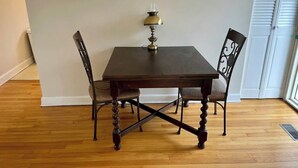 Une table à manger avec quatre chaises, une lampe de table et un radiateur posé sur le sol.