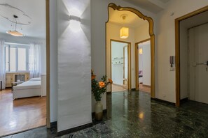 Un pasillo de hotel con una cama, un jarrón con flores y un espejo.