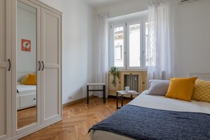 A bedroom with a bed, a bedside table, a chair, a radiator, and a window with curtains. - Casa Gabri by Wonderful Italy (Turin)
