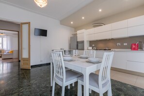 Una cocina moderna con armarios blancos, horno empotrado y refrigerador de acero inoxidable.