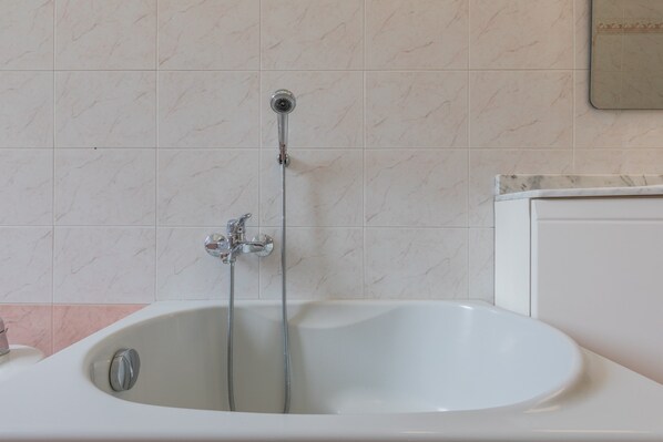 A bathroom with a bathtub, a shower head, and a faucet. - Casa Gabri by Wonderful Italy (Turin)