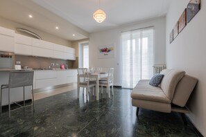 Una cocina moderna con armarios blancos, un comedor con mesa y sillas, y un sofá.