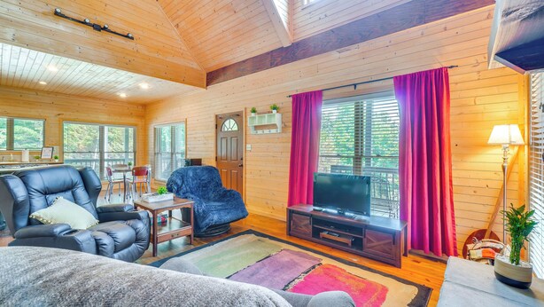 Un interior de cabaña acogedor con un sofá de cuero, un televisor y un comedor.