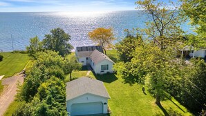 A residential property with a large lawn, a garage, and a house with a sloped roof. - Lakefront 3BD, Home Walk to Downtown Port Sanilac (Port Sanilac)