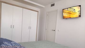 Un dormitorio con cama, televisión en la pared y armario.