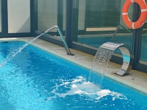 A swimming pool with a water feature, a lifebuoy, and a glass enclosure. - COVACHOS BEACH APARTMENT (Soto de la Marina)