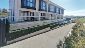 A modern two-story building with large windows and a balcony. - COVACHOS BEACH APARTMENT (Soto de la Marina)