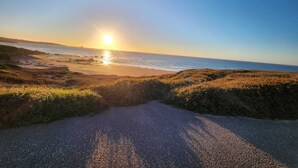 A coastal road leading to the sea with a clear sky and the sun setting or rising. - COVACHOS BEACH APARTMENT (Soto de la Marina)