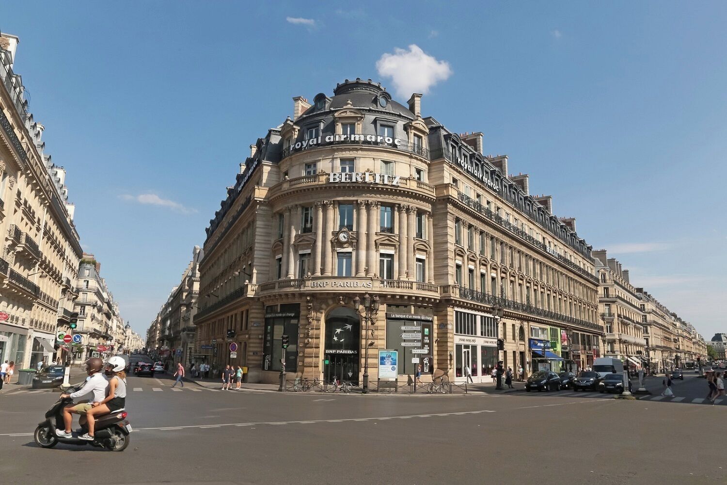 Un bâtiment historique à l’architecture riche et élaborée, caractérisé par une entrée d’angle remarquable et de nombreuses fenêtres.