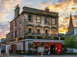 Un edificio histórico con fachada negra y un letrero que dice “Hootananny”, reconocido como el mejor local de música escocesa en Escocia.