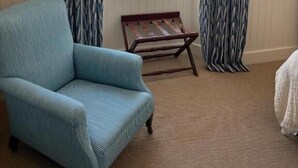 A room with a window, a blue armchair, a wooden bench, and a TV mounted on the wall. - Hootananny  (Inverness)