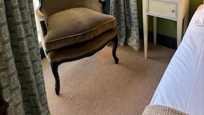 A room with a brown armchair, a bedside table with a lamp, and a bed. - Hootananny  (Inverness)