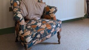 A room with a floral-patterned armchair, a framed artwork, a flat-screen TV, and a radiator. - Hootananny  (Inverness)
