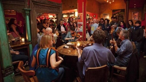 A crowded indoor venue with round tables and chairs, people engaged in conversation, and a warm, dimly lit atmosphere. - Hootananny  (Inverness)