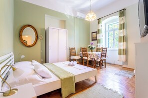 Une chambre à coucher avec un lit, une lampe de chevet et une table entourée de chaises dans la pièce adjacente.