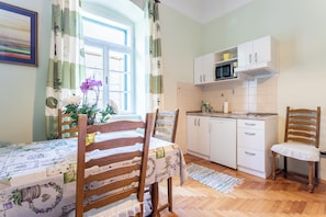Cozy kitchen and dining area with a microwave, tiled backsplash, and wooden table.