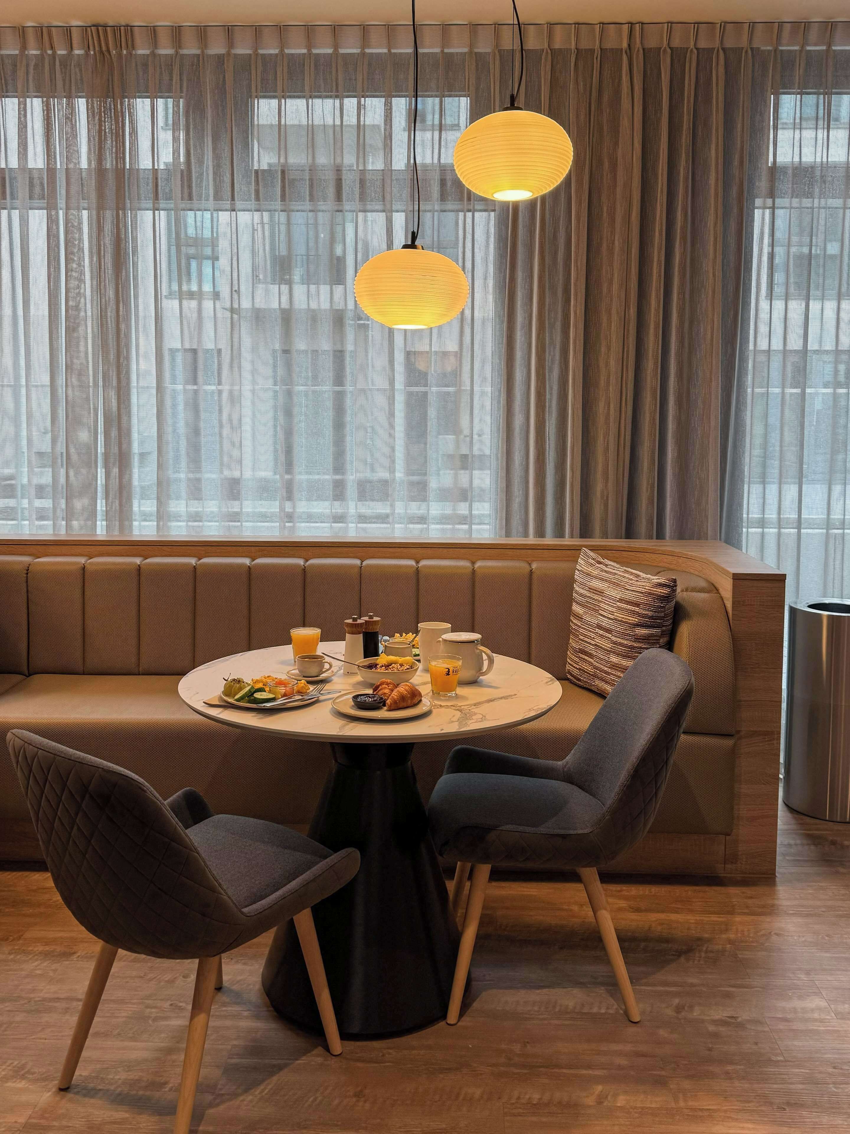 A modern dining area with a round table, two chairs, a sofa, and a breakfast setting.