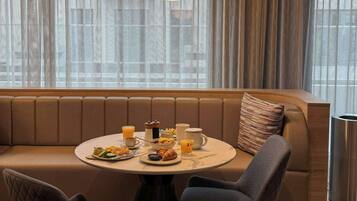 A modern dining area with a round table, two chairs, a sofa, and a breakfast setting.