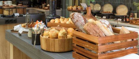 A buffet with various breads, pastries, and a coffee station.