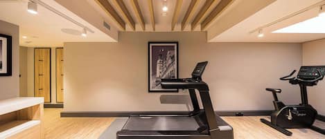 Un gimnasio moderno con una cinta de correr, una máquina elíptica y una bicicleta estática.