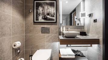 Un baño moderno con suelo de mármol, inodoro, lavabo y un cuadro en la pared.
