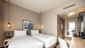 A hotel room with two beds, a desk, a chair, and a large mirror.