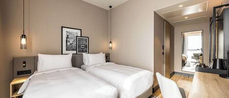A hotel room with two beds, a desk, a chair, and a large mirror.