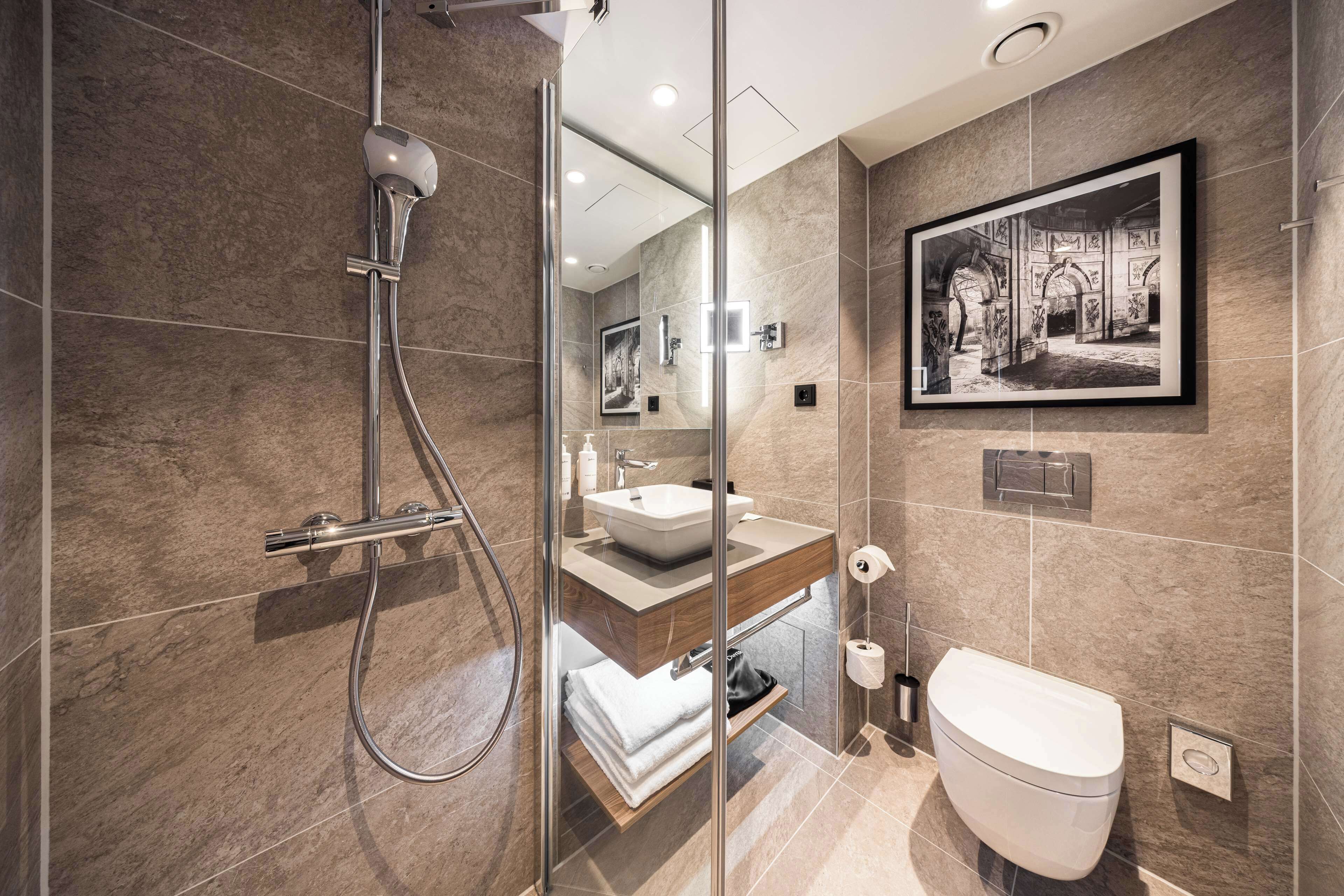 A modern bathroom with a glass-enclosed shower, a sink, and a toilet.