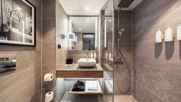 Un baño moderno con un espejo grande, un lavabo, una ducha y un perchero para toallas.