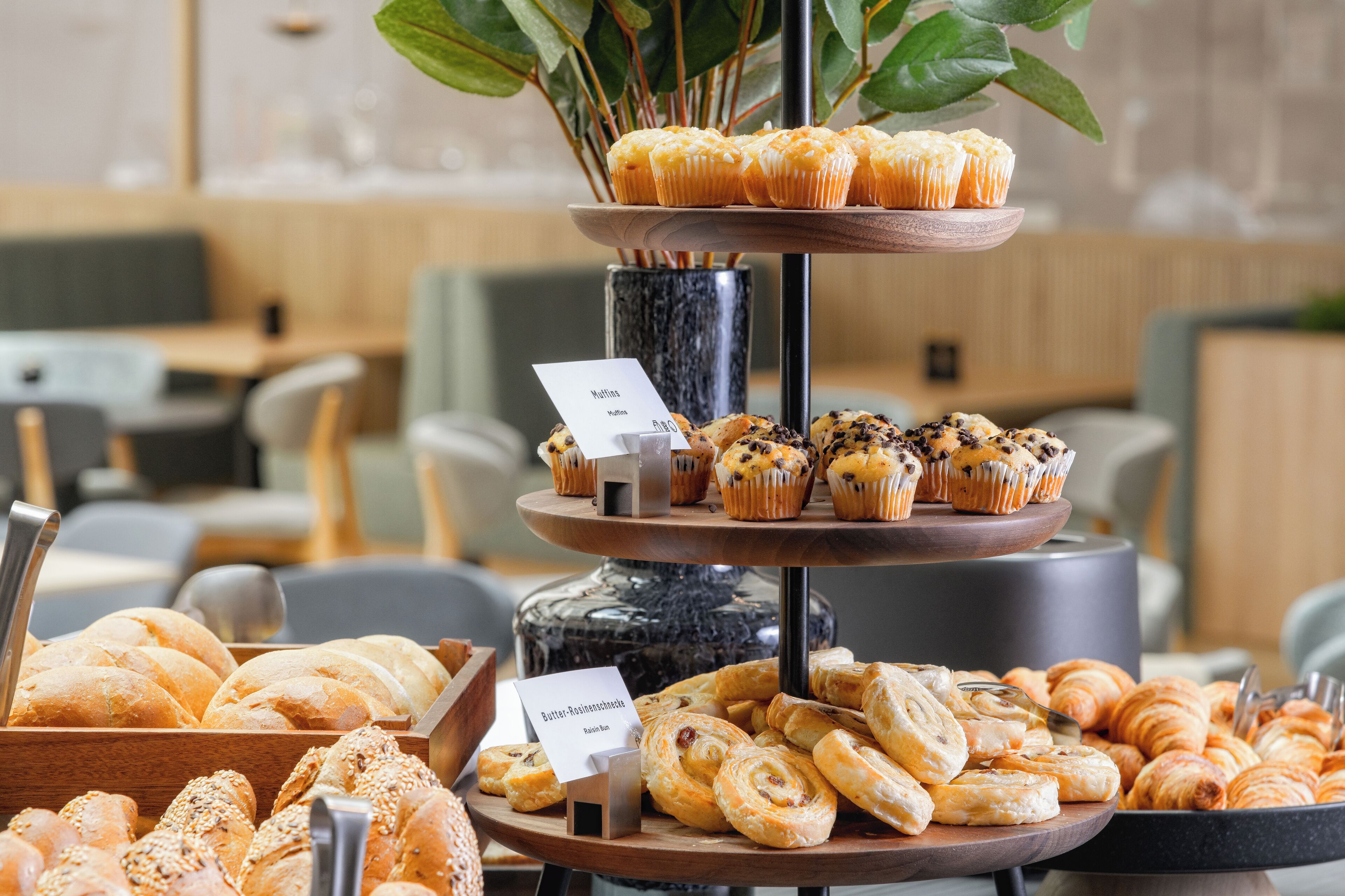 A multi-tiered display of pastries and bread in a cafe setting.