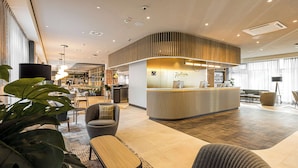 Un rebedor d'hotel modern amb una recepció, zona de seients i grans finestres.
