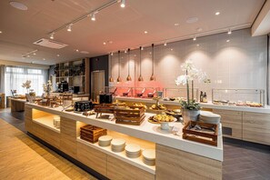 Ein modernes Frühstücksbuffet mit Holztresen, einer vielfältigen Auswahl an Speisen und einem hellen, sauberen Innenraum.