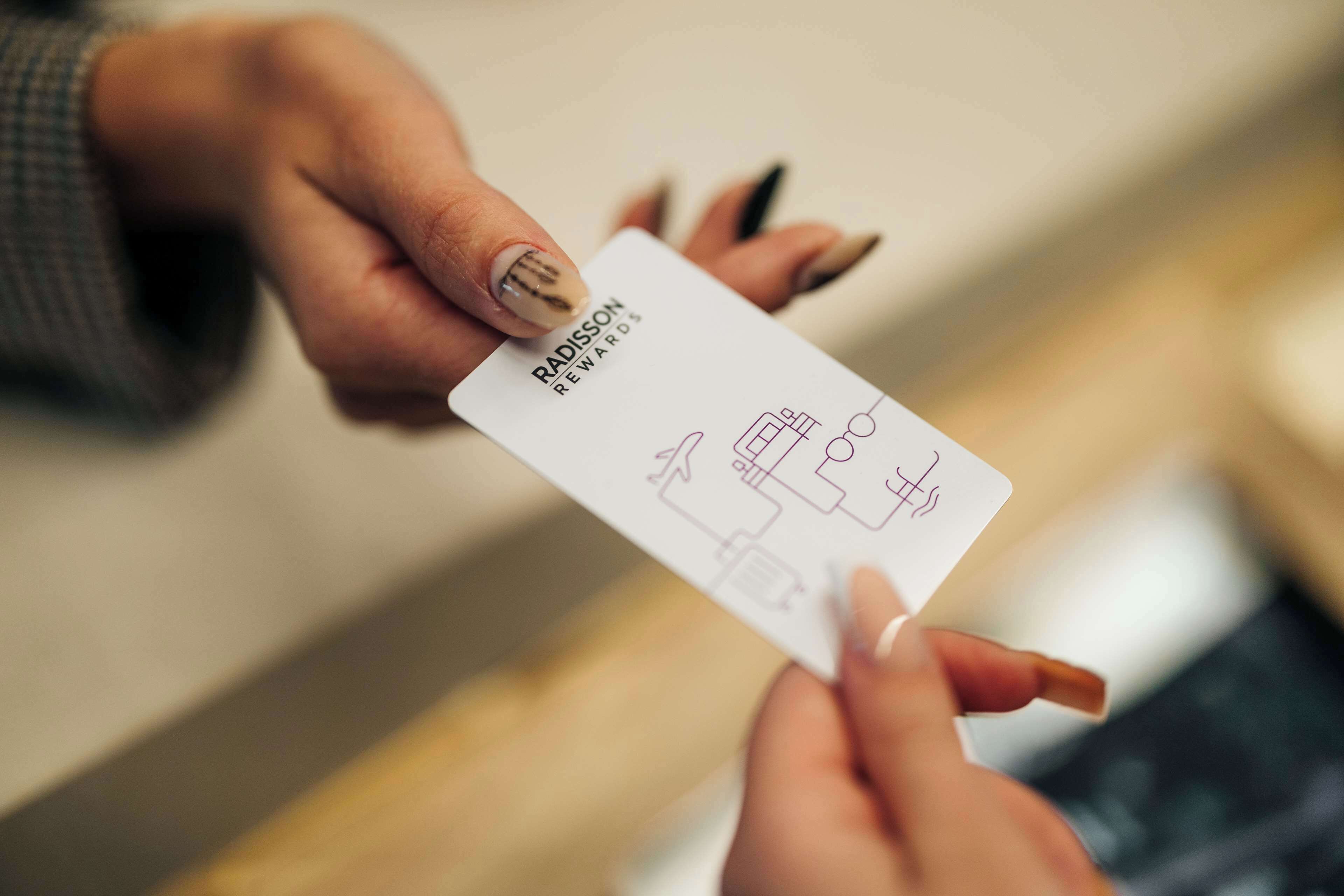 A person holding a card with the text "RADISSON REWARDS" and a diagram of a building.