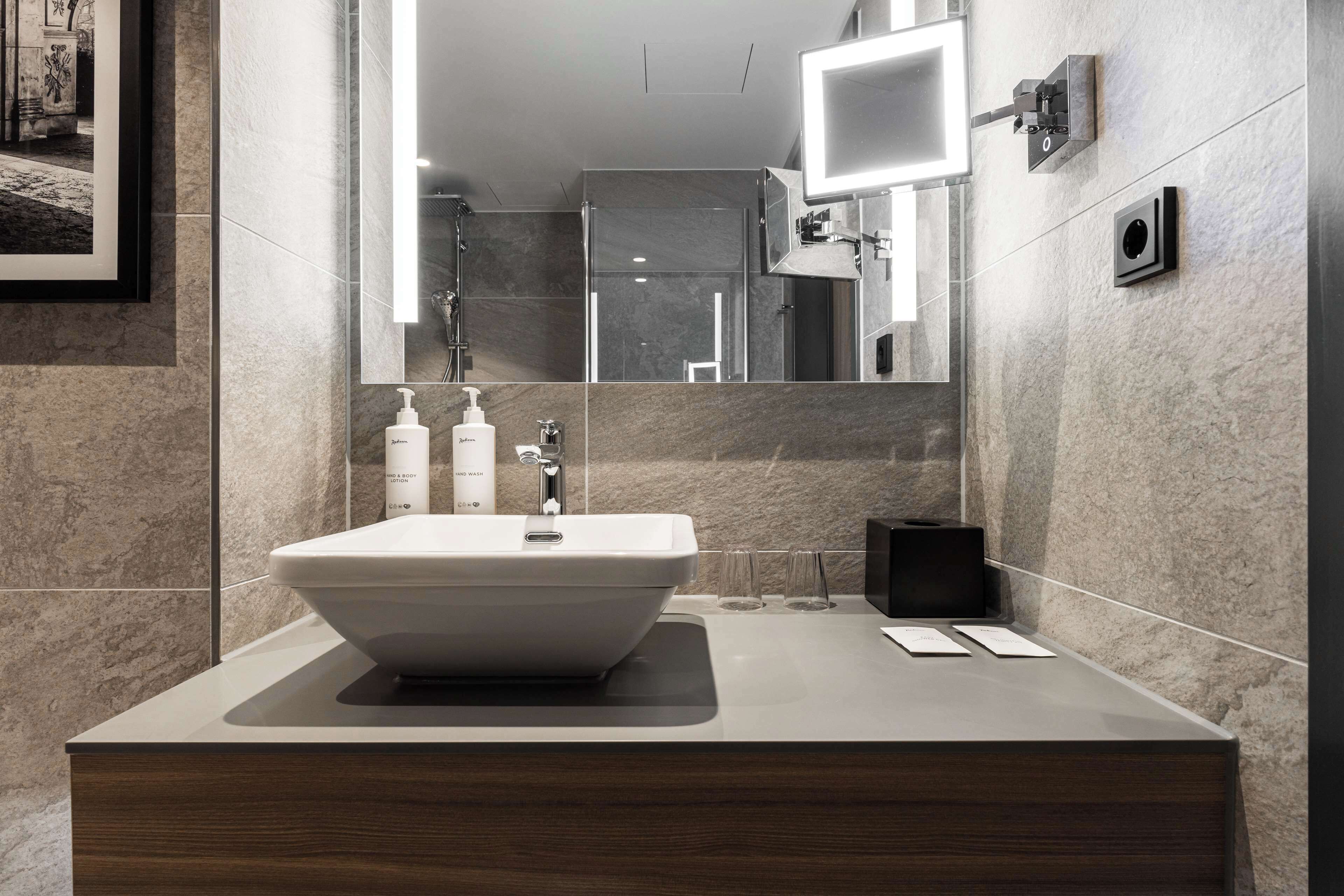 A modern bathroom with a large sink, a mirror, and a shower.