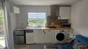 Una cocina compacta con lavadora, microondas y un refrigerador pequeño.