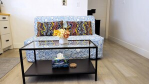 Una sala de estar moderna con un sofá estampado, una mesa de centro de vidrio y un pequeño objeto decorativo sobre la mesa.