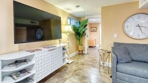 A living room with a flat-screen TV, a clock, a sofa, and a plant. - Private Underground Getaway - 92 WalkScore (Portland)