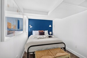 Bedroom with a blue accent wall and woven bench.