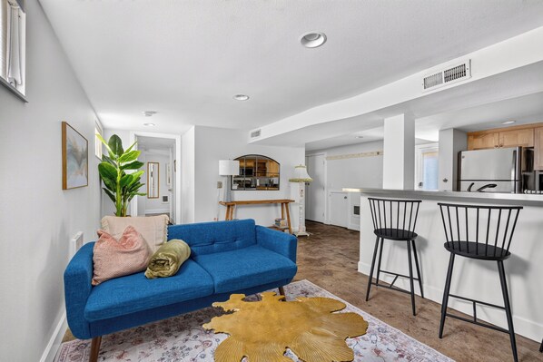 Open living area with blue sofa and kitchen breakfast bar.