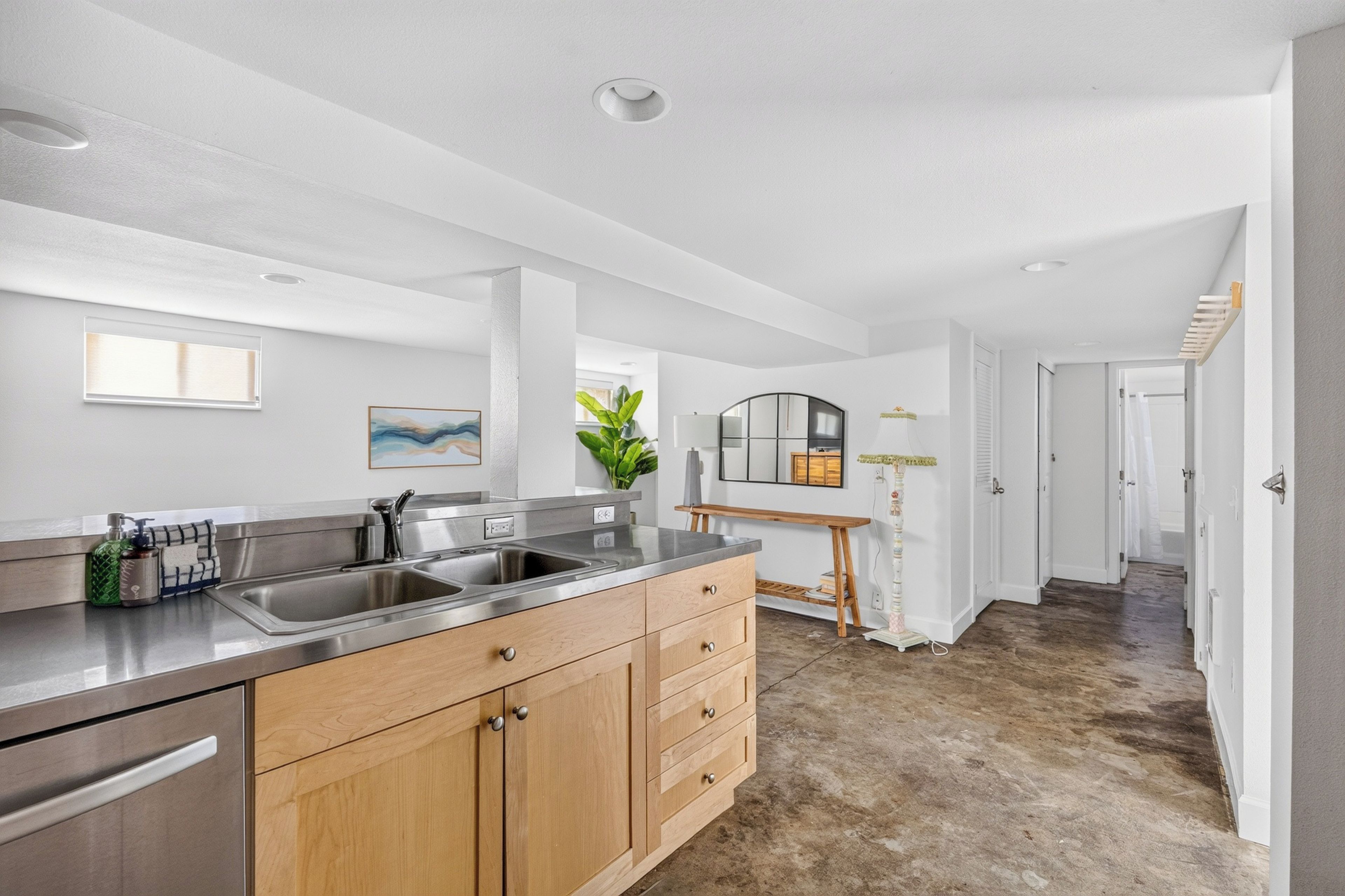 A modern kitchen with stainless steel appliances, wooden cabinets, and a large window.