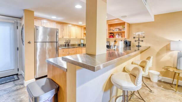A modern kitchen with stainless steel appliances, wooden cabinets, and a bar area with stools. - Private Underground Getaway - 92 WalkScore (Portland)